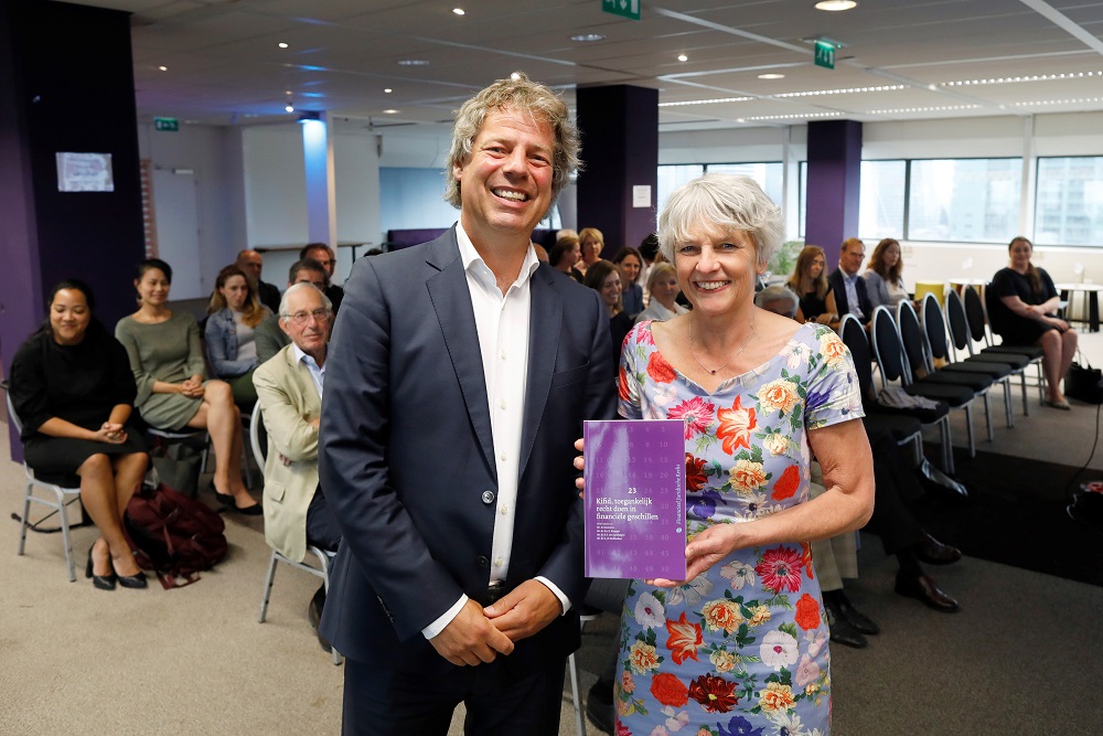 Gijs Molkenboer van de redactieraad van FJR overhandigt het eerste exemplaar van het boek van en over Kifid aan Eveline Ruinaard. Foto Wiebe Kiestra.