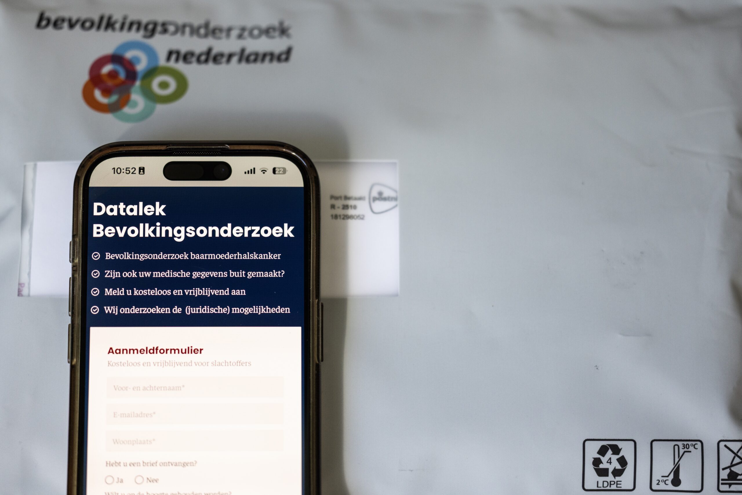 De website datalekbevolkingsonderzoek.nl op een telefoon en een pakket van de bevolkingsonderzoek naar baarmoederhalskanker. Tienduizenden vrouwen van wie gegevens zijn gestolen bij de hack bij laboratorium Clinical Diagnostics, hebben zich al aangesloten bij initiatieven voor een mogelijke collectieve schadeclaim. ANP
