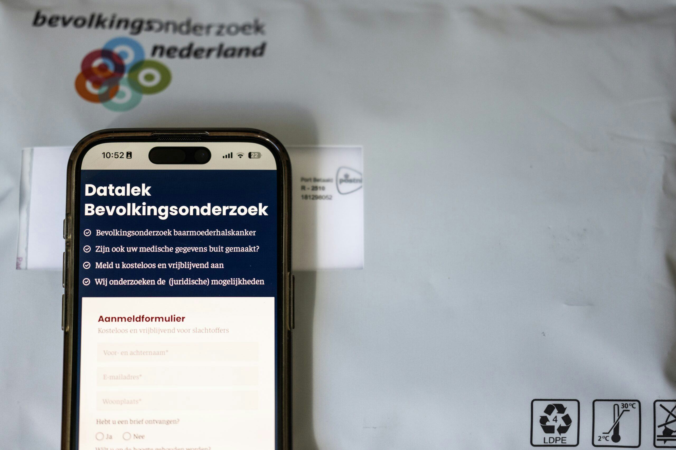 De website datalekbevolkingsonderzoek.nl op een telefoon en een pakket van de bevolkingsonderzoek naar baarmoederhalskanker. Tienduizenden vrouwen van wie gegevens zijn gestolen bij de hack bij laboratorium Clinical Diagnostics, hebben zich al aangesloten bij initiatieven voor een mogelijke collectieve schadeclaim. ANP